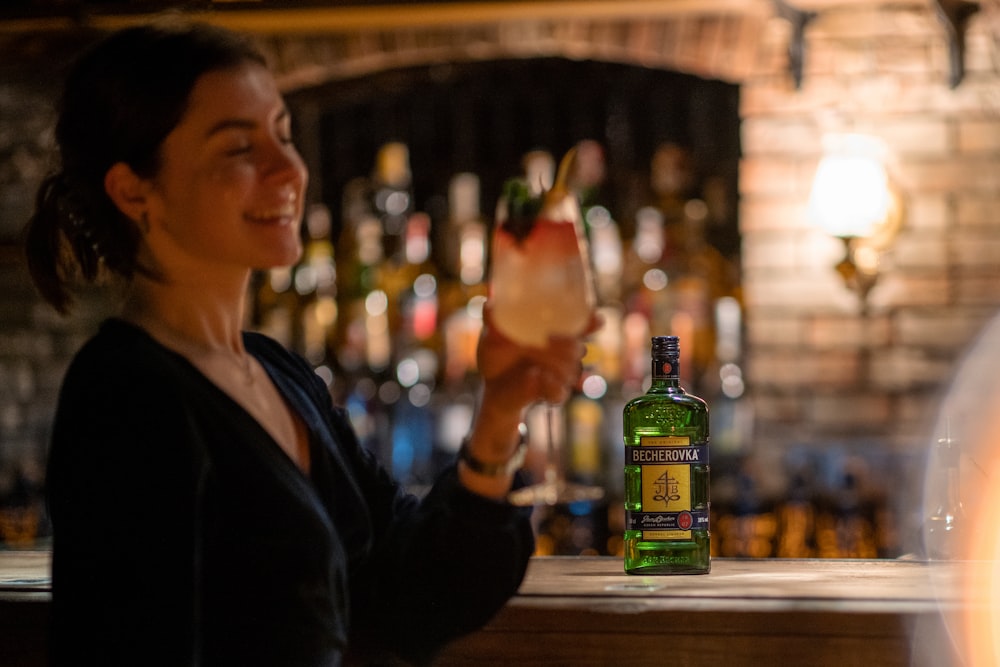 a woman sitting at a bar with a bottle of alcohol