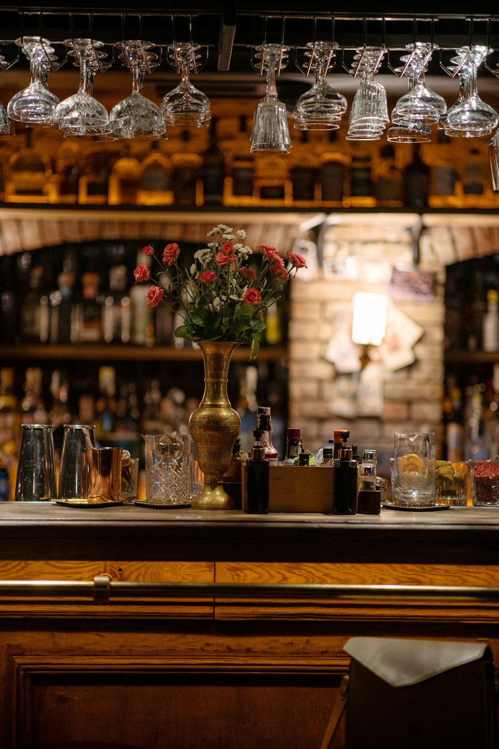 a bar with a vase of flowers and glasses on it