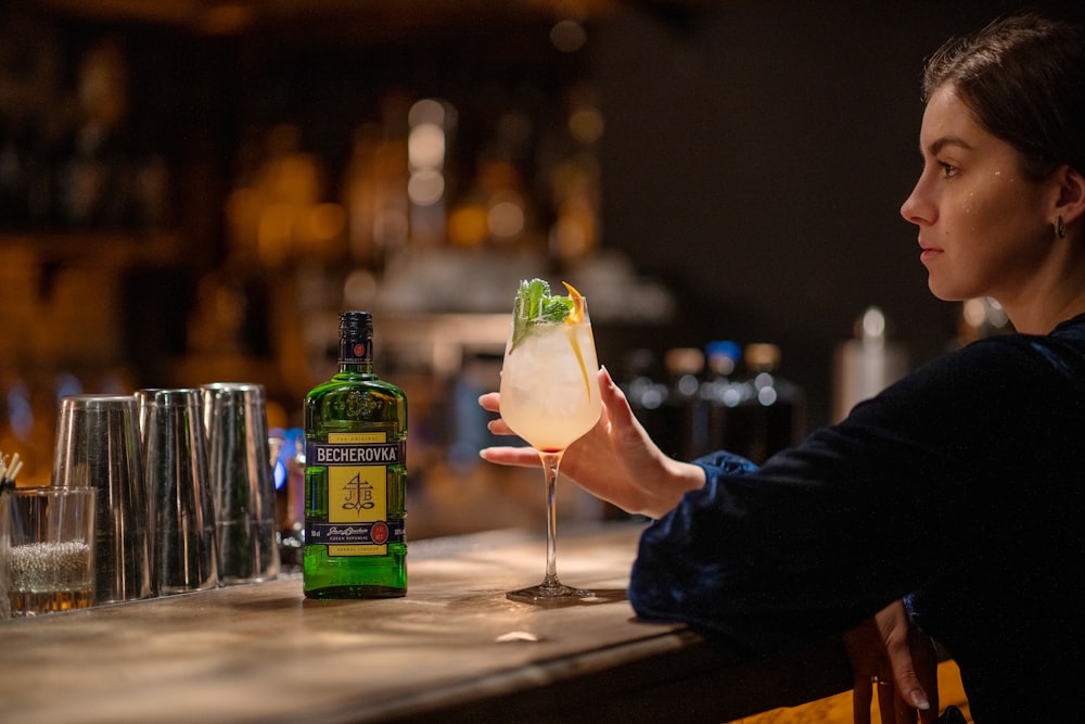 a woman sitting at a bar holding a drink