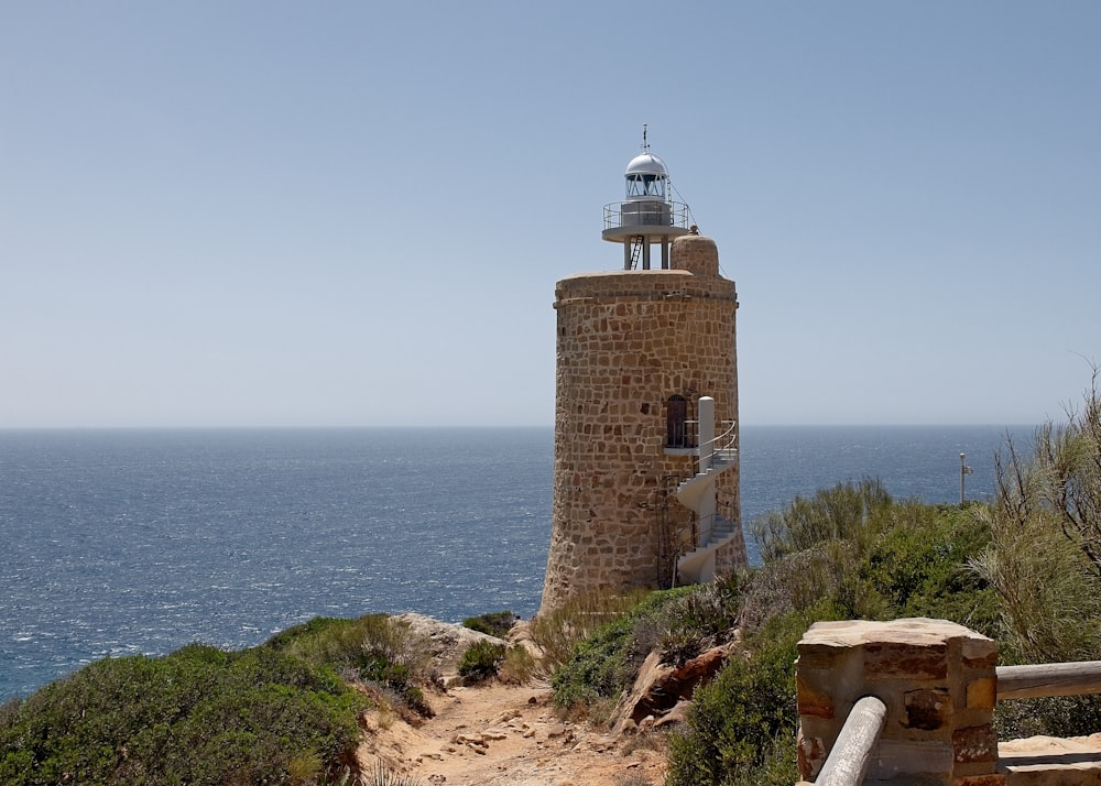 a light house sitting on top of a hill next to the ocean