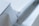 A close-up view of a modern, minimalist white object with sharp edges and geometric shapes. The design is sleek and clean with a focus on angular forms and subtle details.