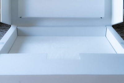 A clean, white cardboard box is open, revealing an empty interior. The box is well-lit, showing crisp edges and subtle shadows. It appears to be a package ready for use, possibly for shipping or storage.