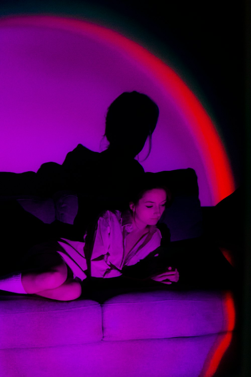 a woman sitting on a couch in front of a purple light