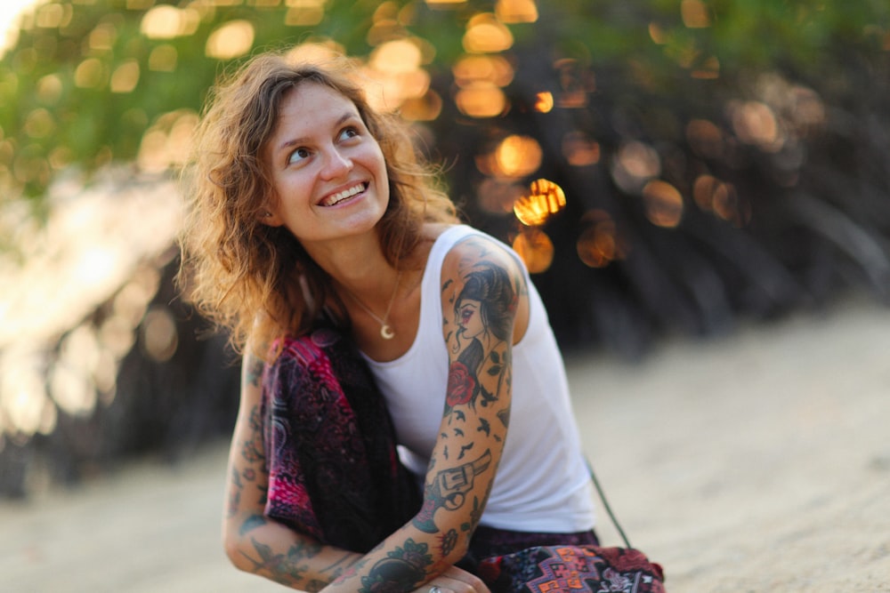 a woman with tattoos sitting on the ground