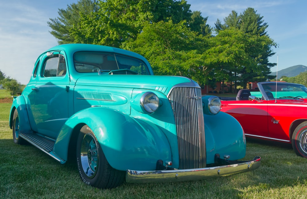 two classic cars parked next to each other in a field