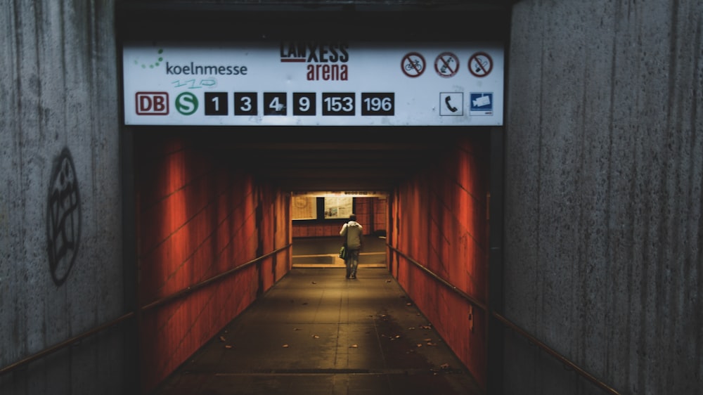a person walking down a tunnel with a sign above it