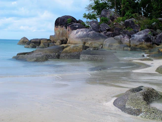 a sandy beach with large rocks and water