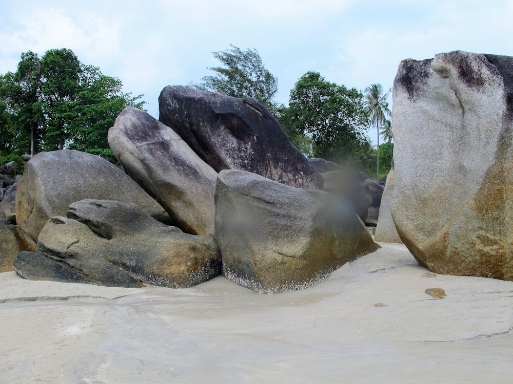 a group of large rocks sitting on top of a sandy beach