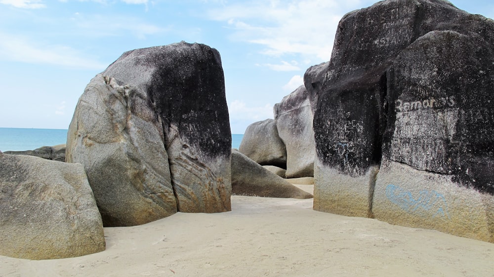 a couple of large rocks sitting on top of a sandy beach