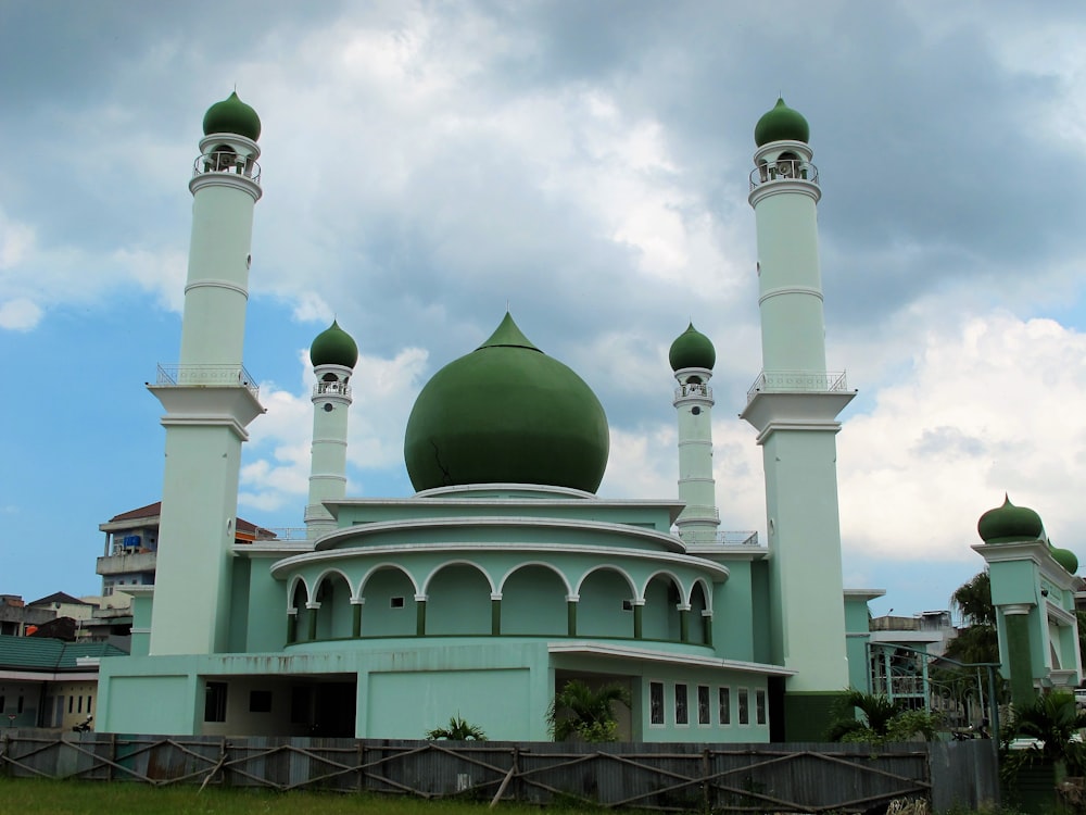 a green and white building with two green domes
