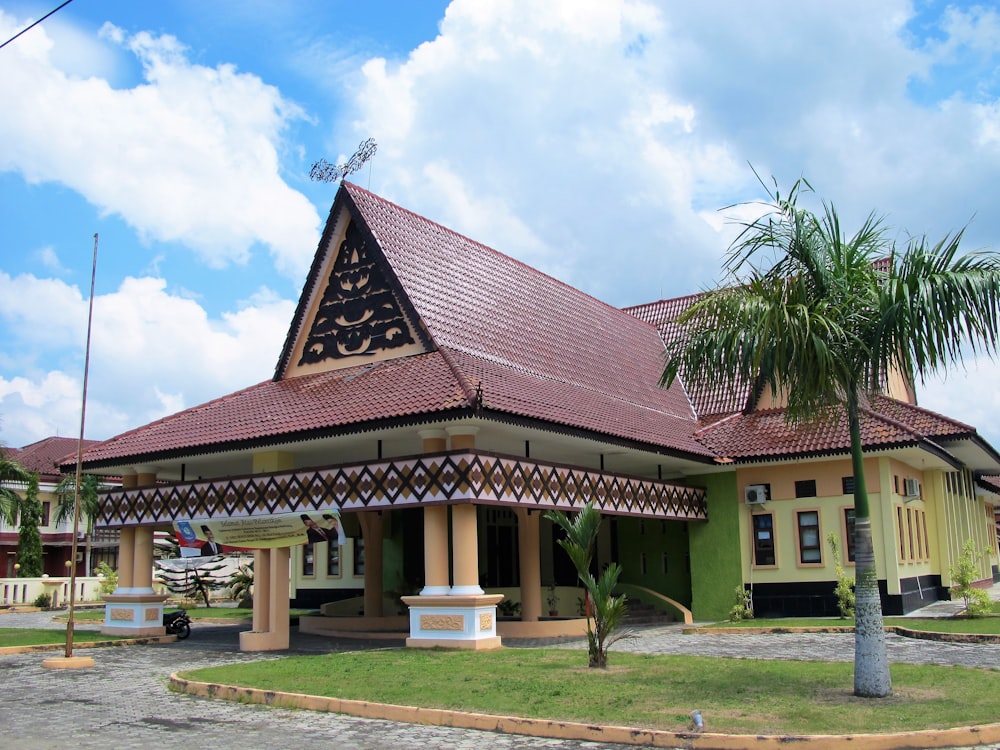 a green and brown building with a palm tree in front of it