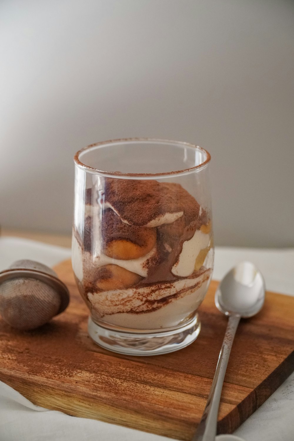 a wooden tray topped with a glass filled with dessert