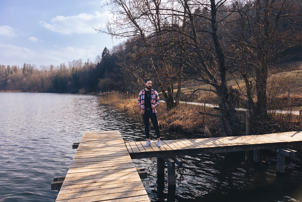 a man standing on a dock next to a body of water