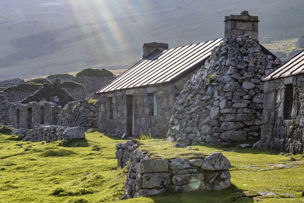 a stone building with a metal roof and a rainbow in the background