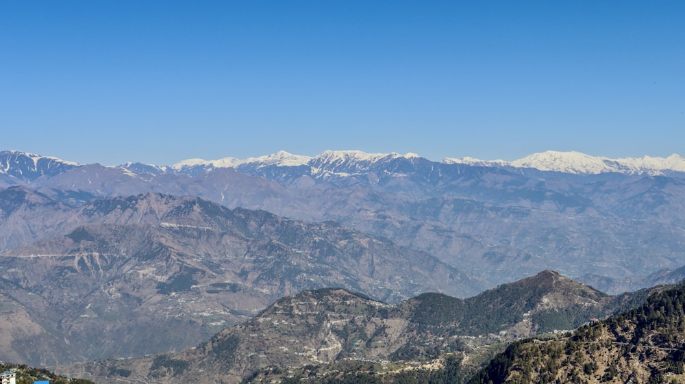 a scenic view of a mountain range with snow capped mountains in the distance