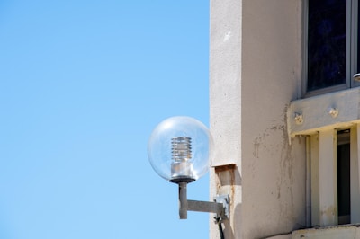 Close-up of a modern solar light fixture installed on a home exterior with a clear sky background.