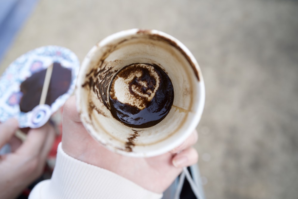 a person holding a cup with a chocolate swirl in it