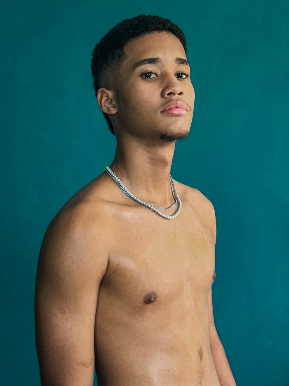 a shirtless young man wearing a chain around his neck
