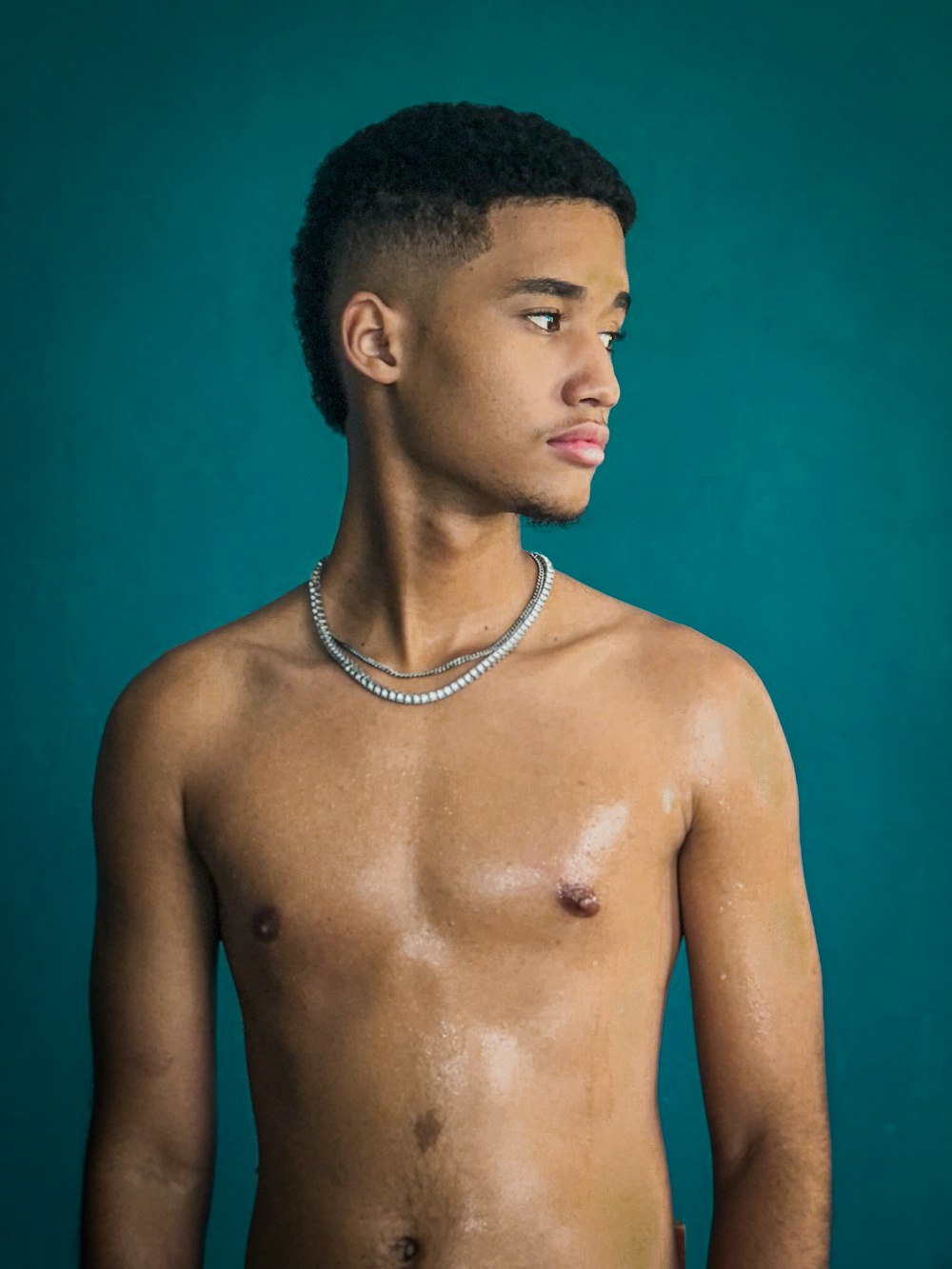 a shirtless man with a necklace on his neck