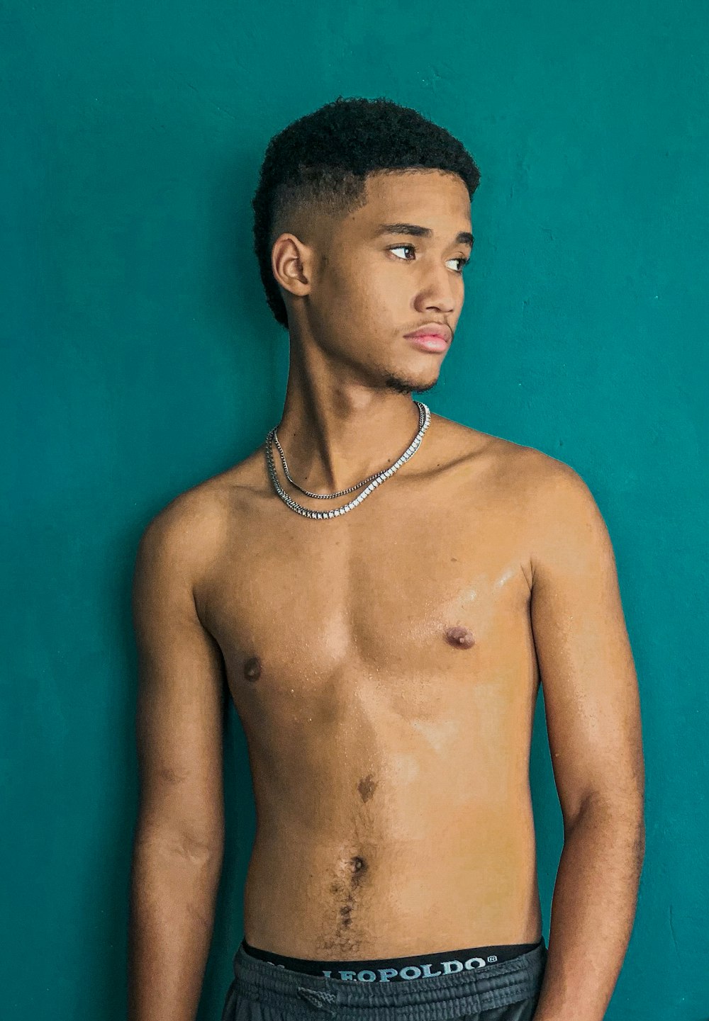 a man with no shirt standing in front of a blue wall
