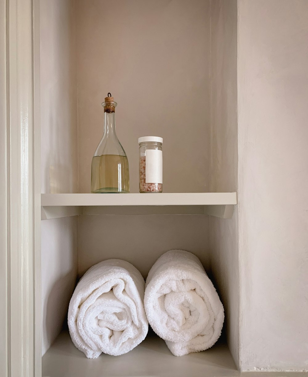 a shelf with two white towels and a bottle
