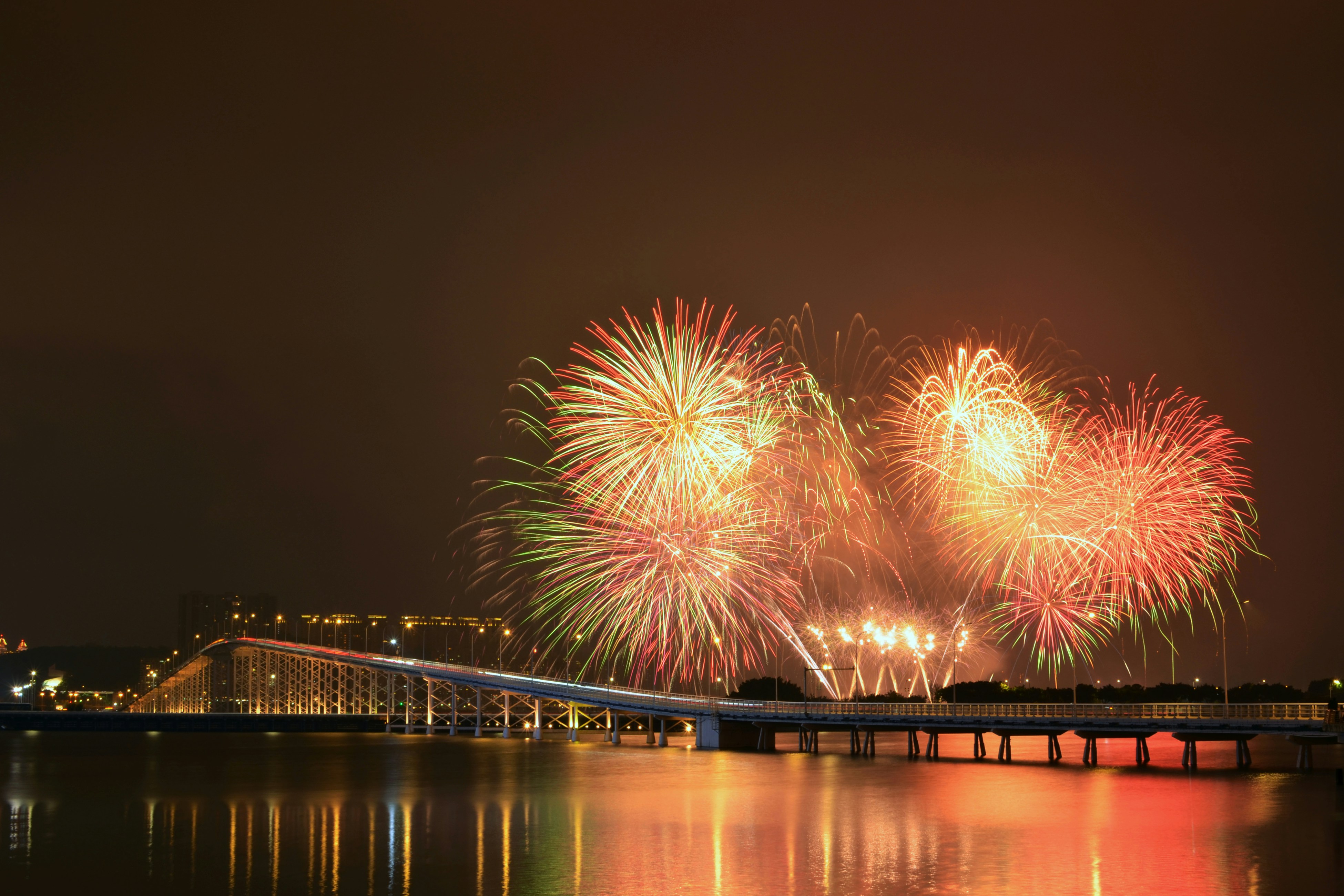 fireworks are lit up in the night sky over a body of water