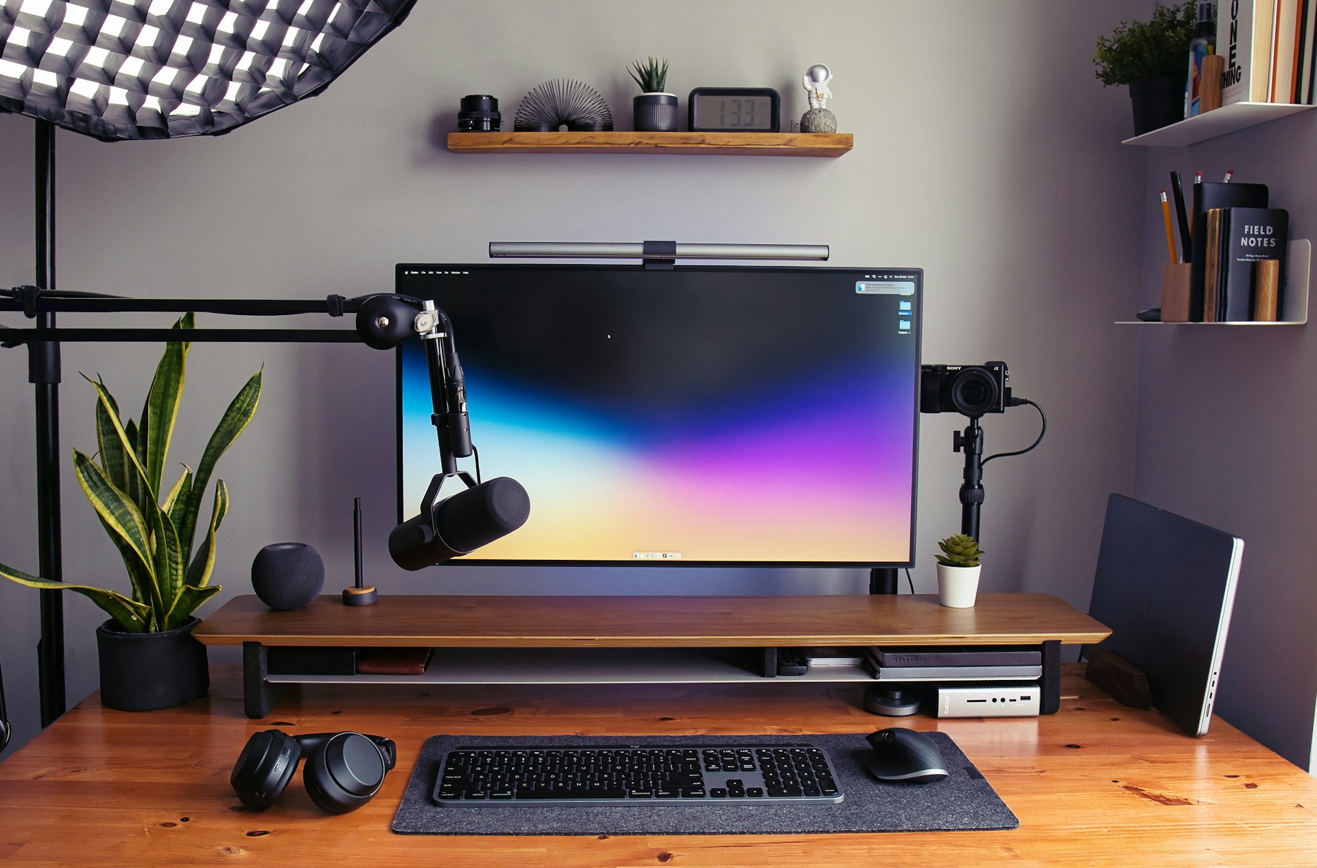 a desk with a monitor, keyboard and headphones