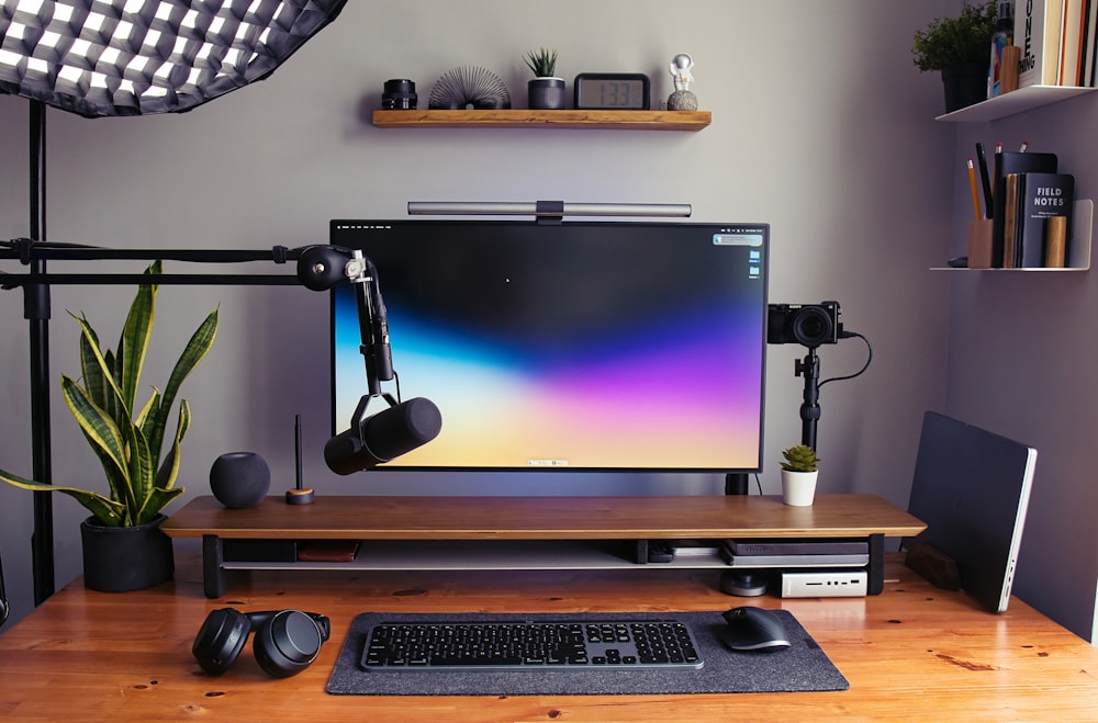 a desk with a monitor, keyboard and headphones
