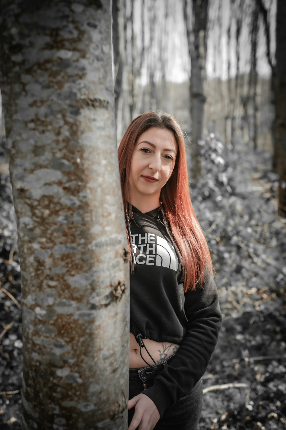 Una mujer parada junto a un árbol en un bosque