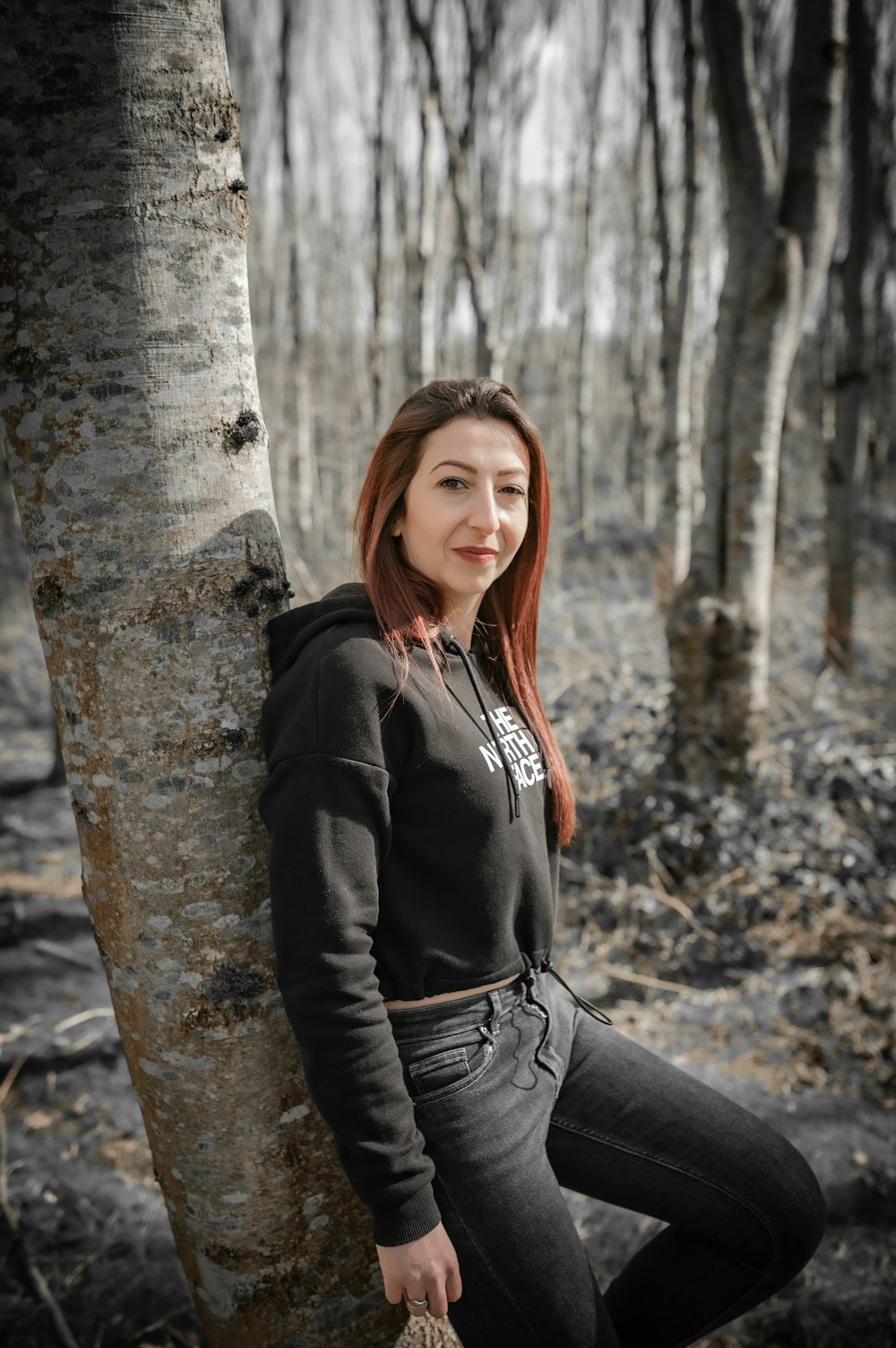 a woman sitting on a tree in a forest