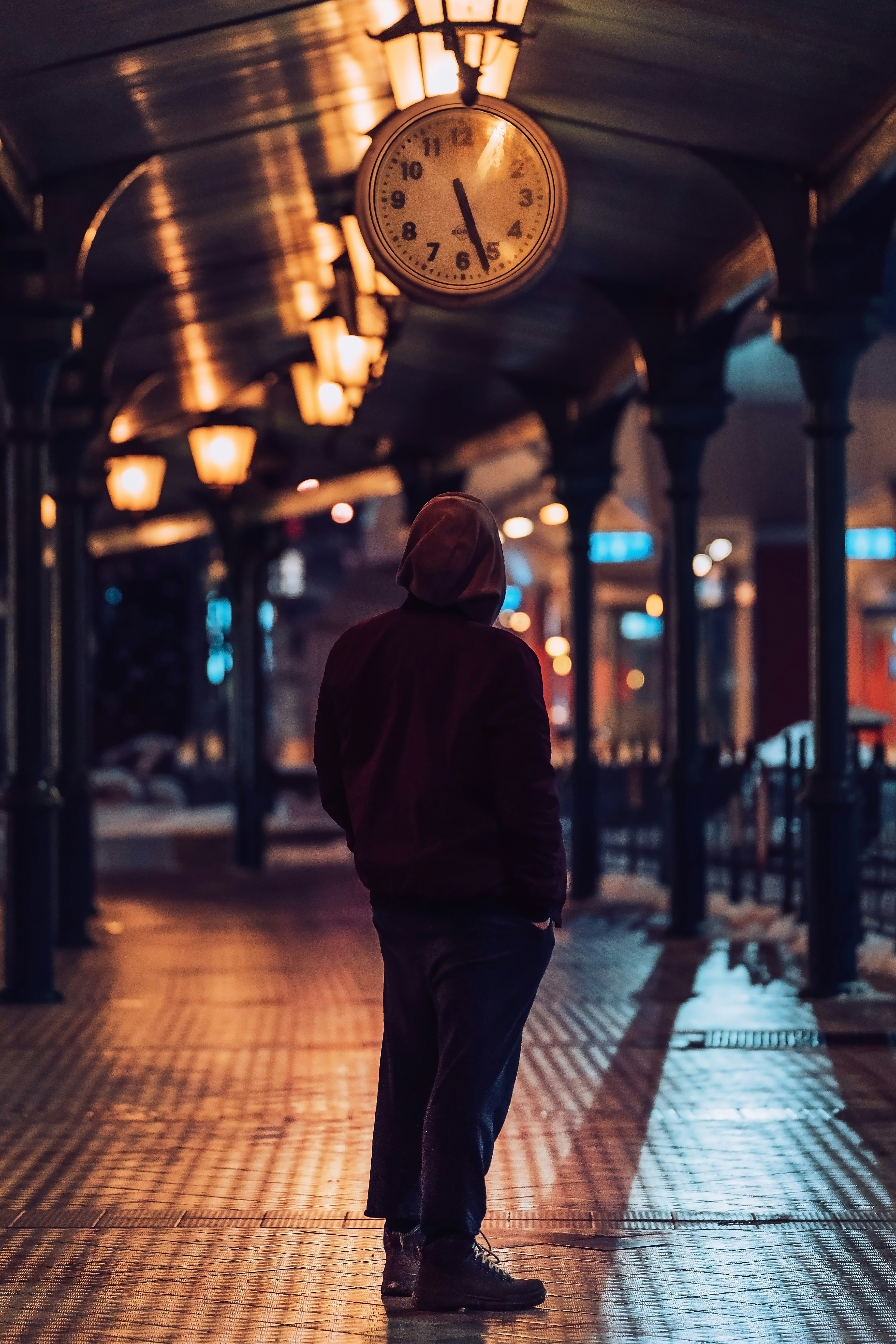 a man standing under a clock in a train station