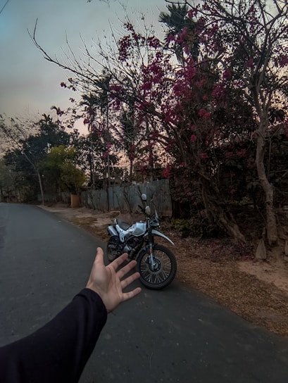 A tow truck assisting a stranded motorcycle on a quiet country road at sunset.