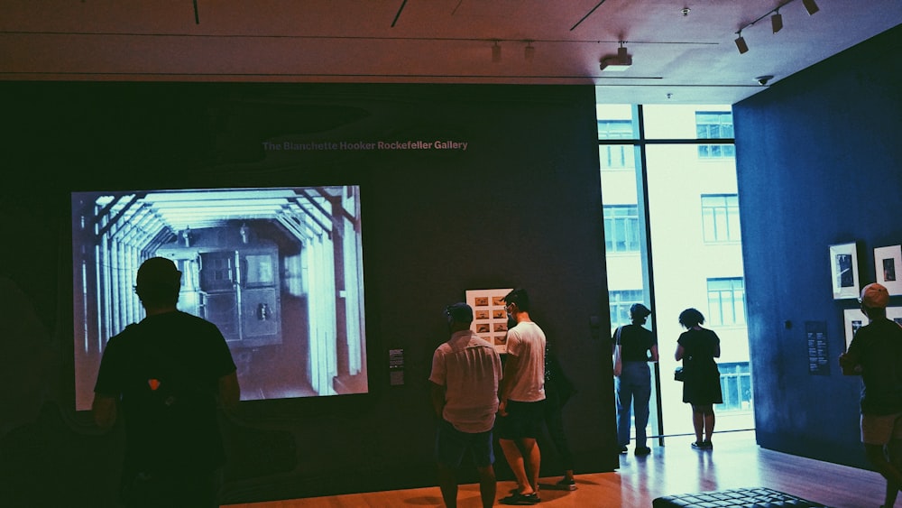 a group of people standing in front of a large screen