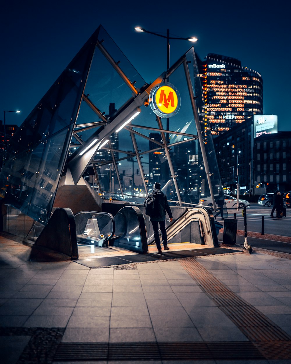 Un uomo è in piedi su una scala mobile in una città di notte