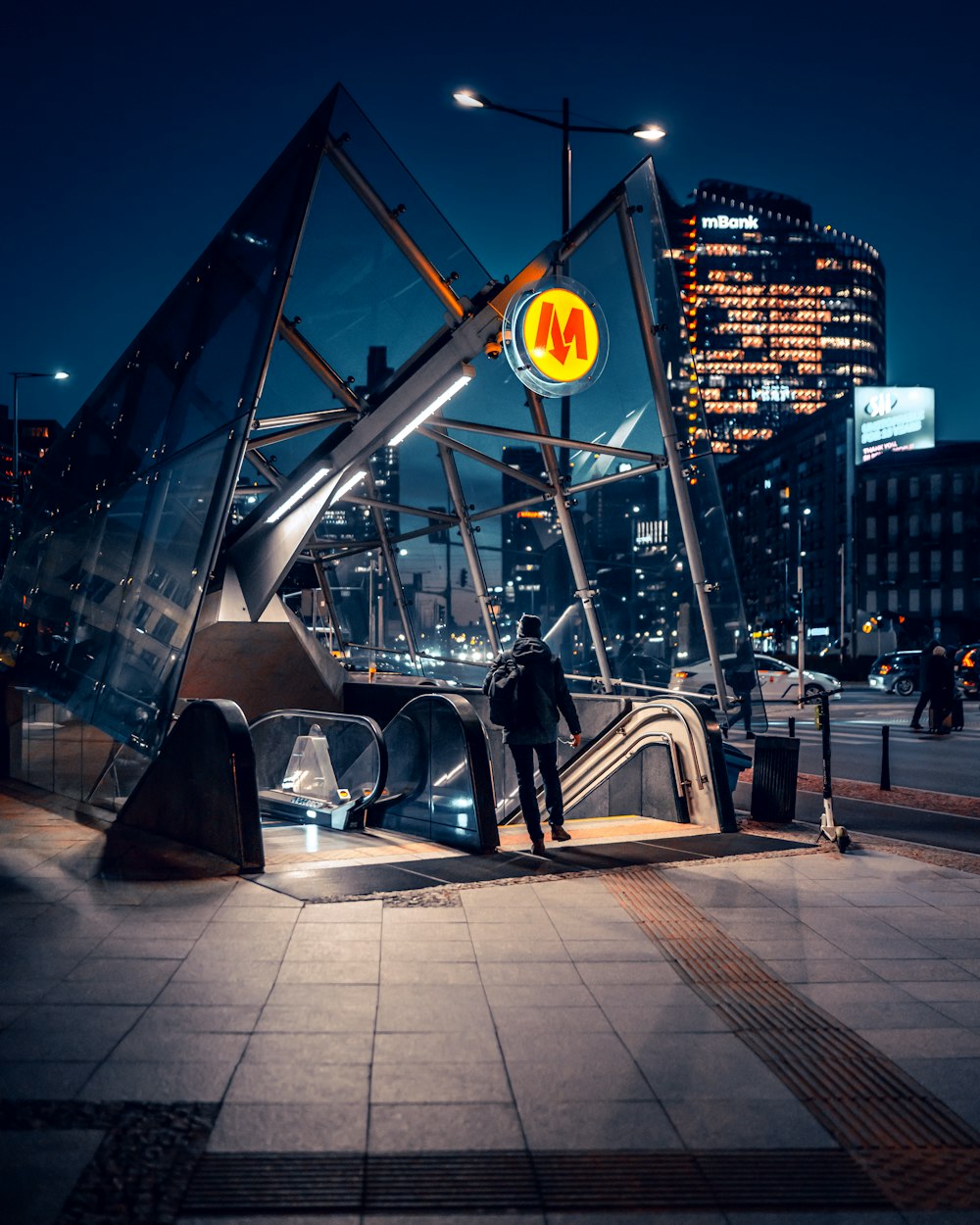 a man is standing on an escalator in a city at night