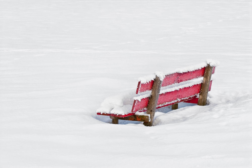 a red bench sitting in the middle of a snow covered field