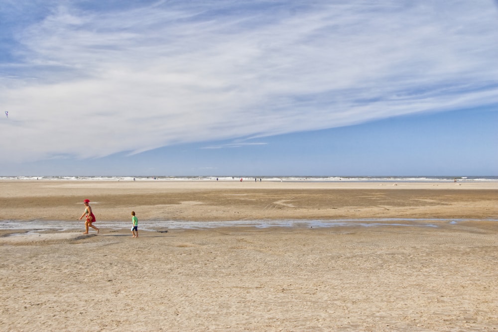 a man and a child are flying a kite on the beach