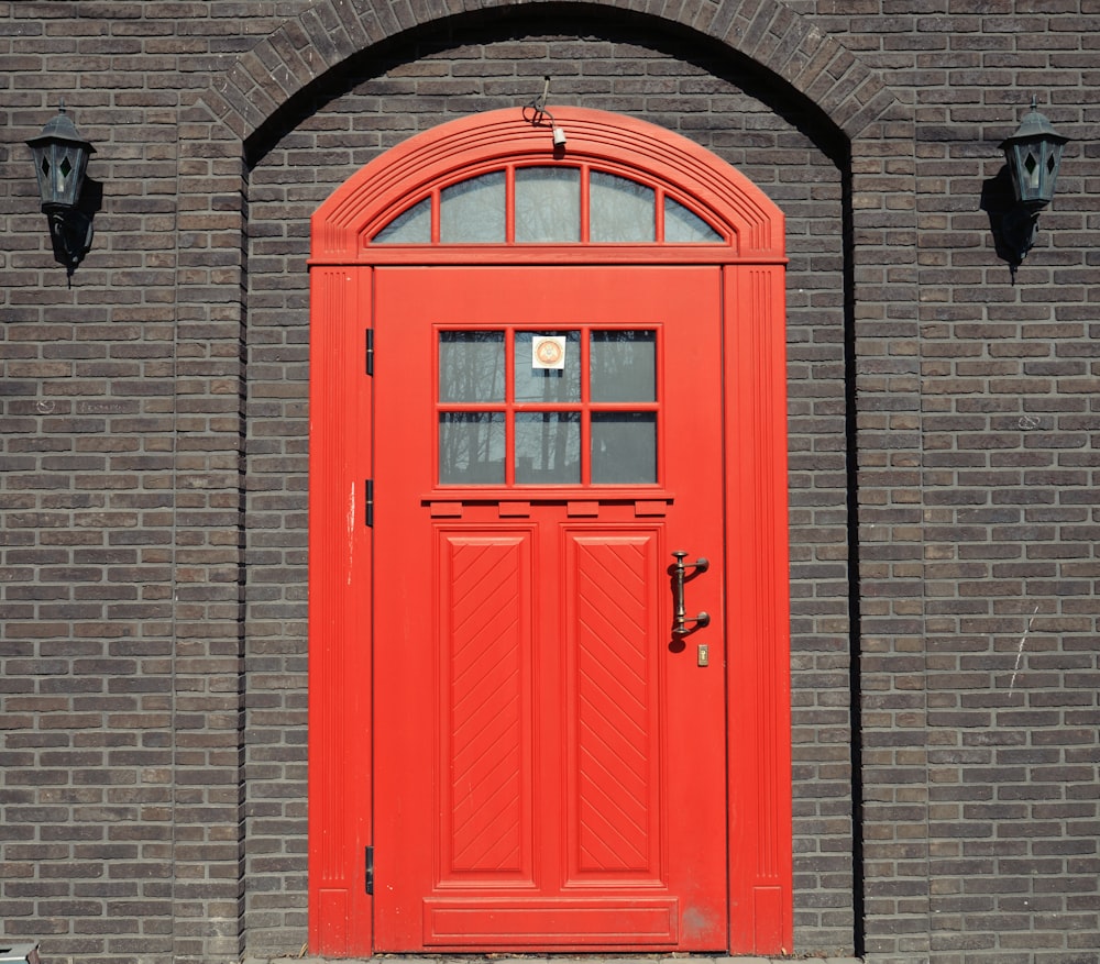 Una puerta roja está frente a un edificio de ladrillo