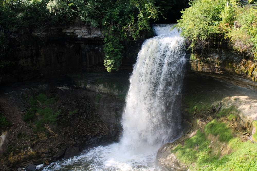 a waterfall with a man standing at the top of it