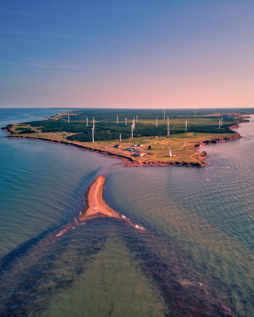 an aerial view of a small island with wind turbines in the background