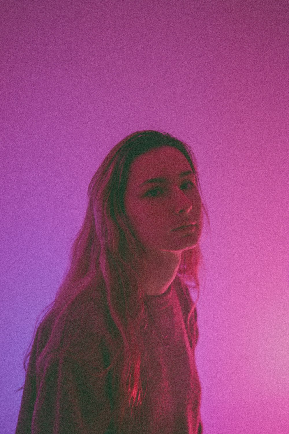 a woman standing in front of a pink and purple background