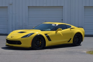 A sporty car fitted with custom large wheels parked outside the garage on a sunny day
