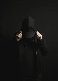 a person wearing a black hoodie and a black hat