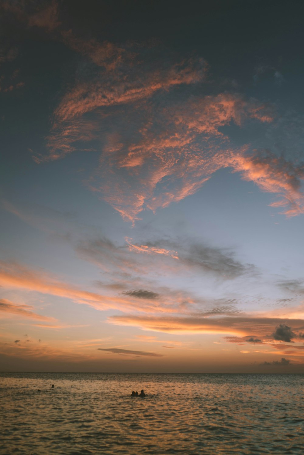 Una puesta de sol sobre un cuerpo de agua con un bote en la distancia