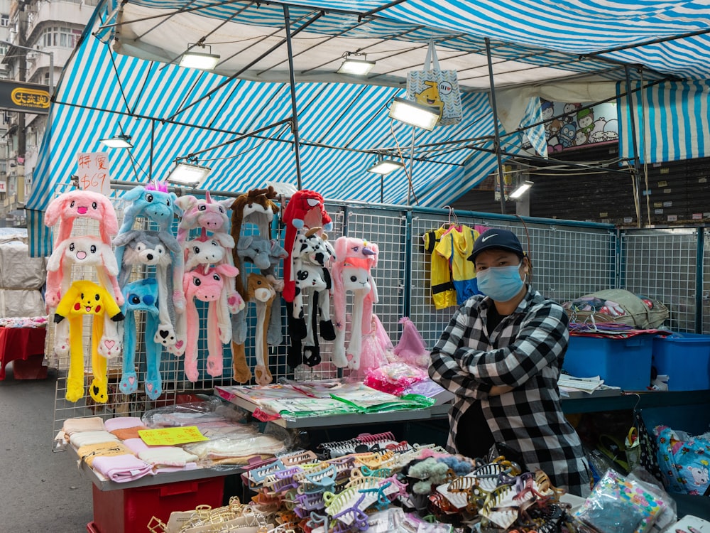 a man wearing a face mask standing in front of a display of stuffed animals