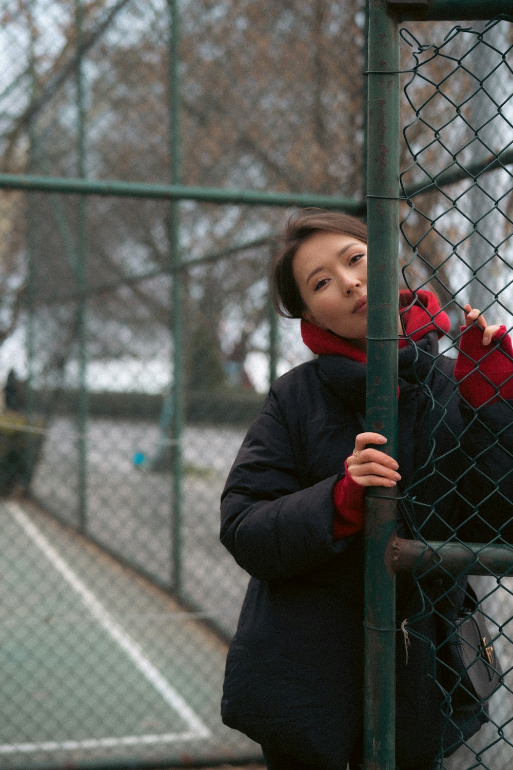 a woman leaning against a fence with a tennis racket