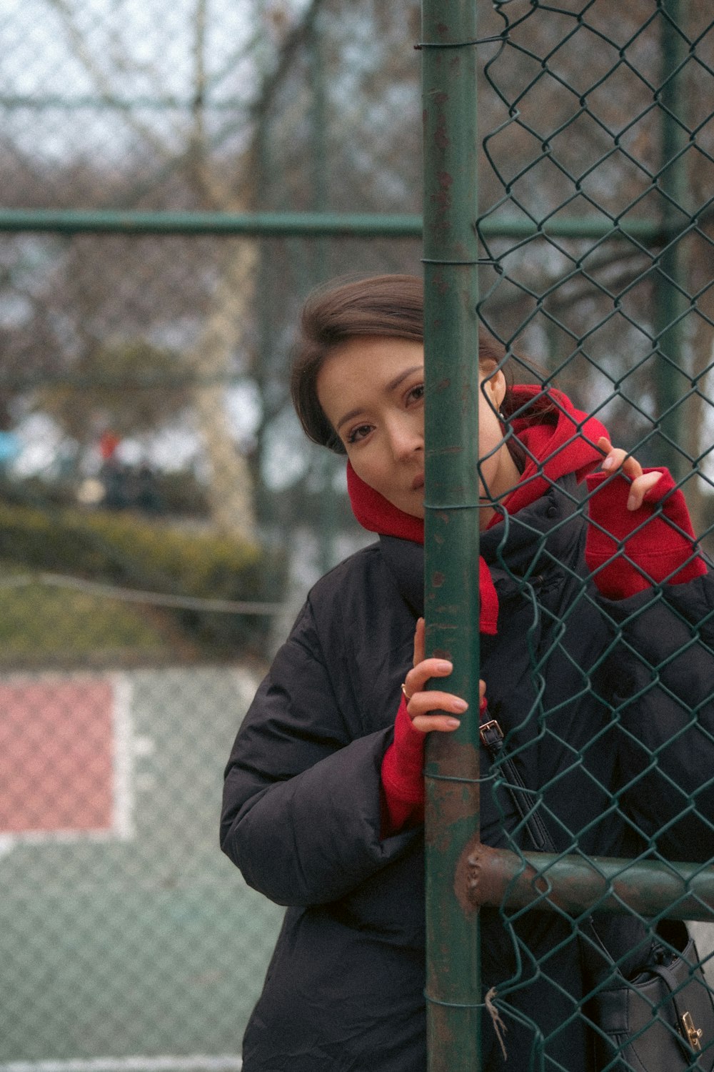 a woman leaning against a fence with her hand on the side of the fence