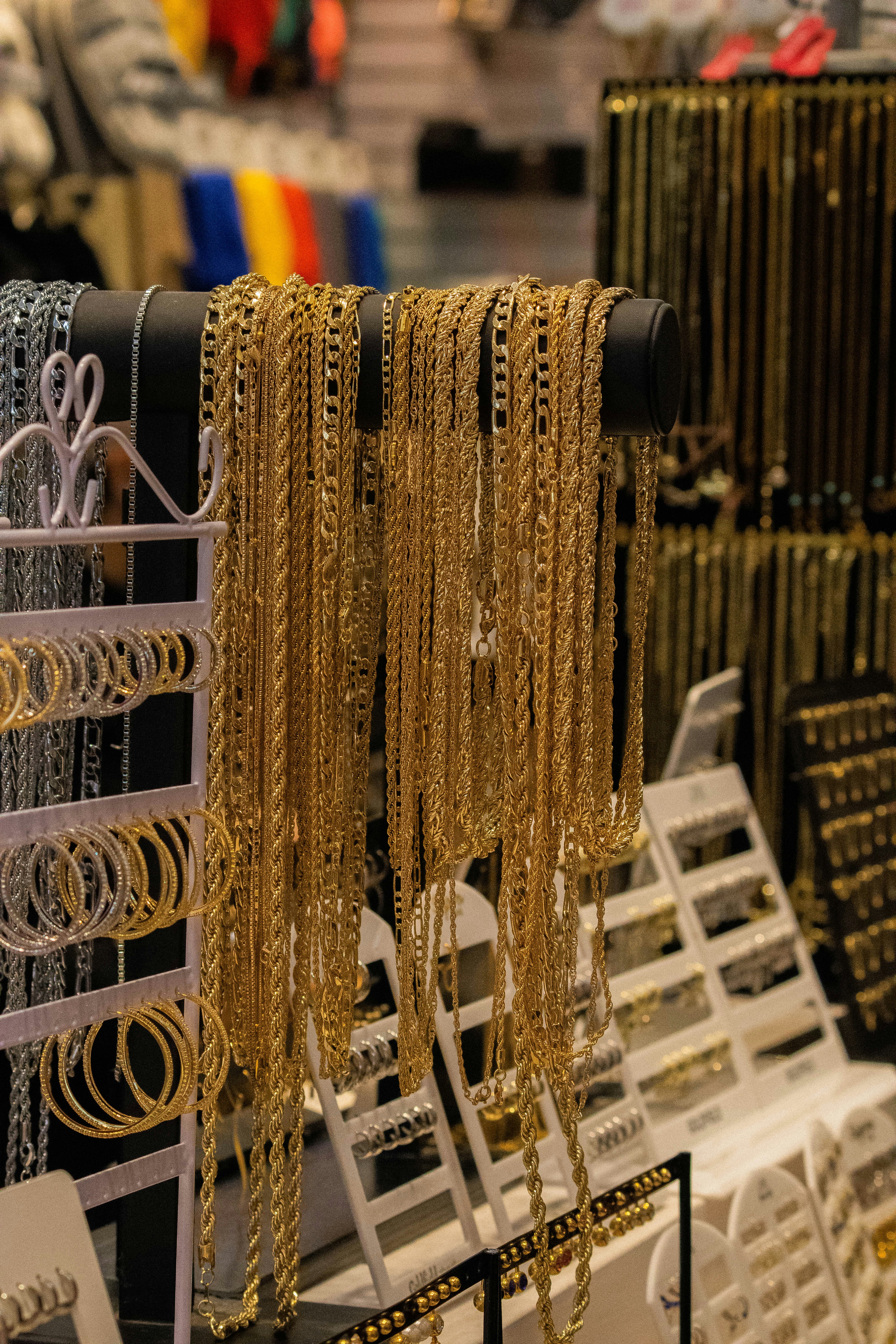 Gold chains and hoop earrings displayed on jewelry stands.