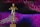 A golden statue resembling an award is centrally placed against a dynamic background of swirling patterns in shades of pink, purple, and blue. The statue stands on a base with the phrase 'DO WHATEVER IT TAKES' engraved on it.