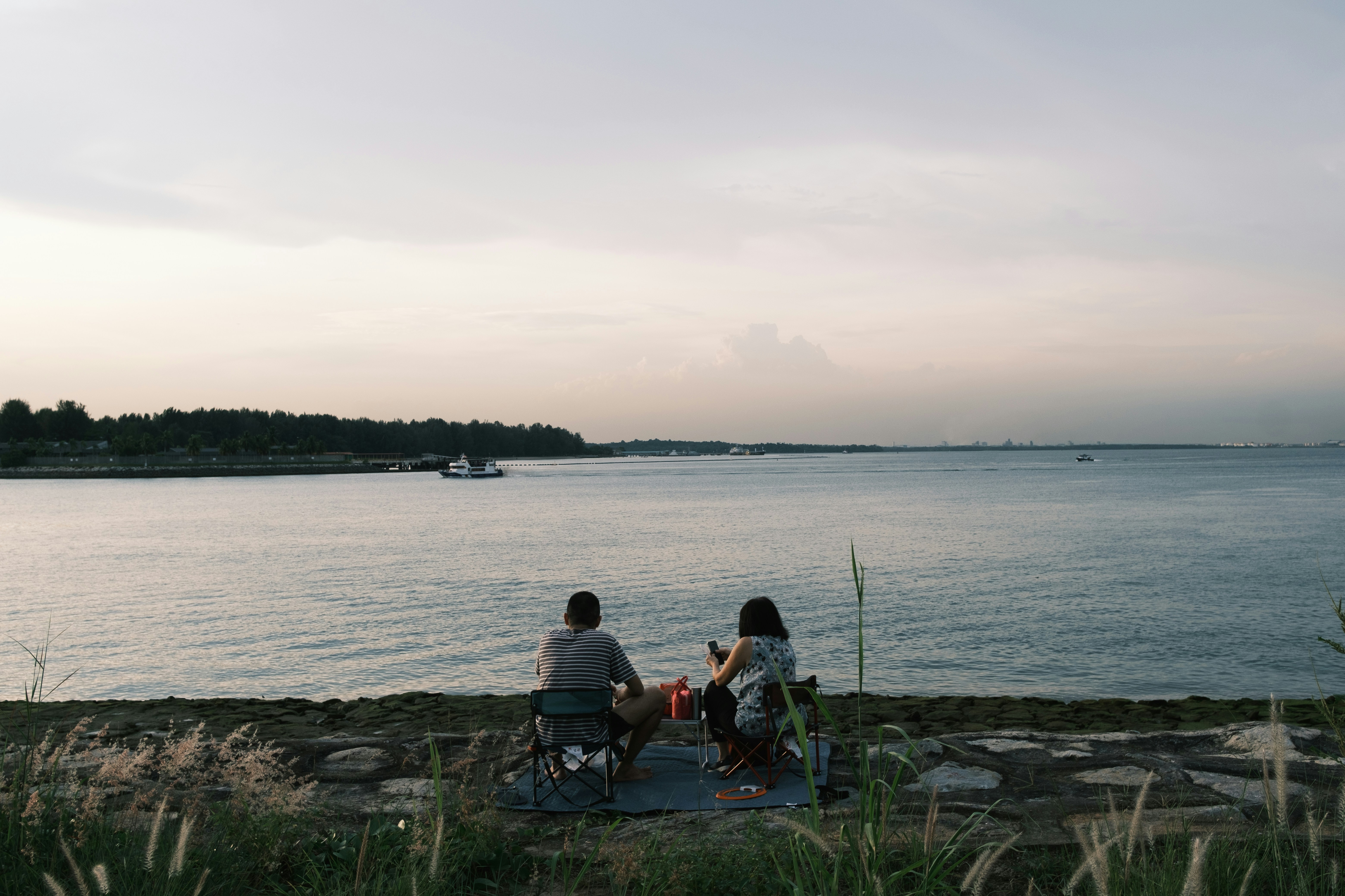 a couple of people sitting on top of a beach next to a body of water